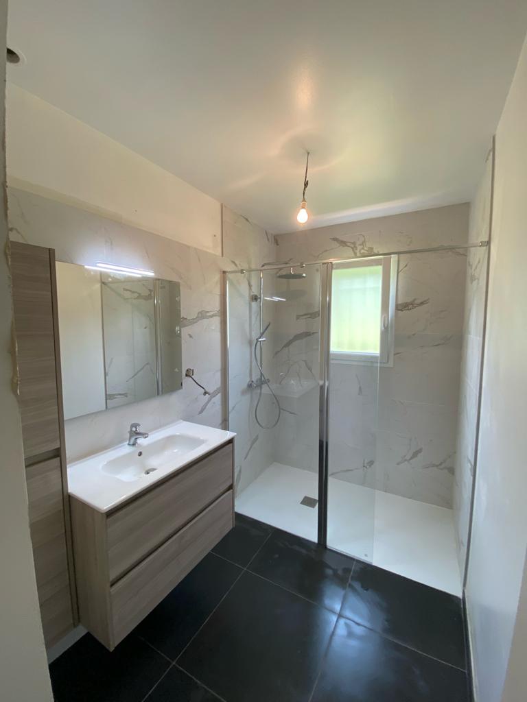 Salle de bain rénovée avec douche à l’italienne et faïence effet marbre
