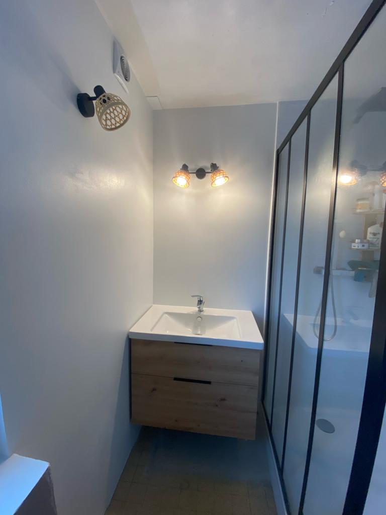 Petite salle d’eau rénovée avec meuble vasque bois et paroi de douche noire