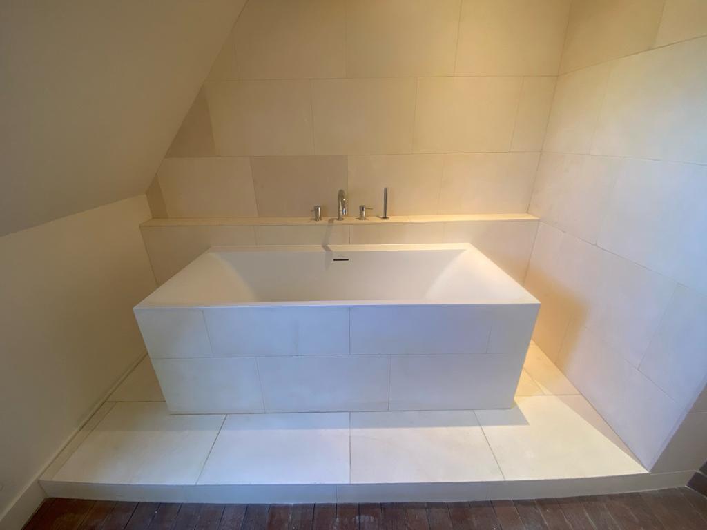 Baignoire habillée de carrelage clair sous rampant